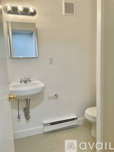 A bathroom with a sink, toilet, and mirror.