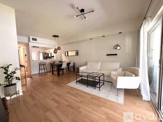 A modern dining room with a black table and white chairs.