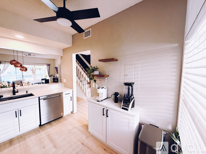 A kitchen with white cabinets and a black ceiling fan.