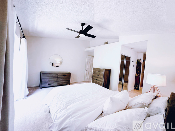 A bedroom with a large bed and a ceiling fan.