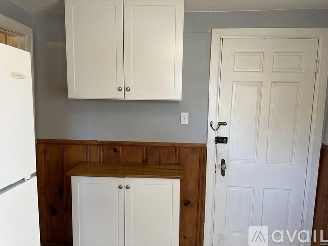 A kitchen with white cabinets and a white door.