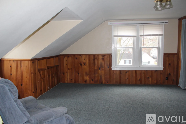 A room with wooden walls and a window with blinds.