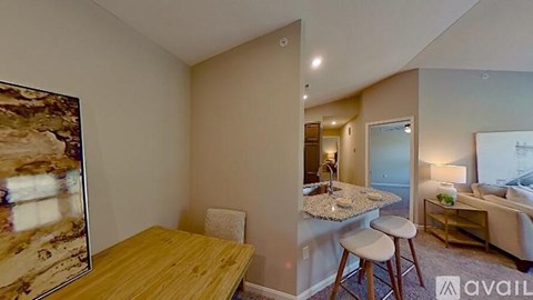 A living room with a couch, a chair, a dining table, and a painting on the wall.
