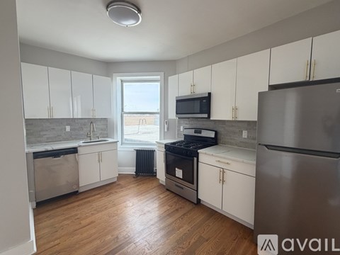 A kitchen with white cabinets and a stainless steel refrigerator.