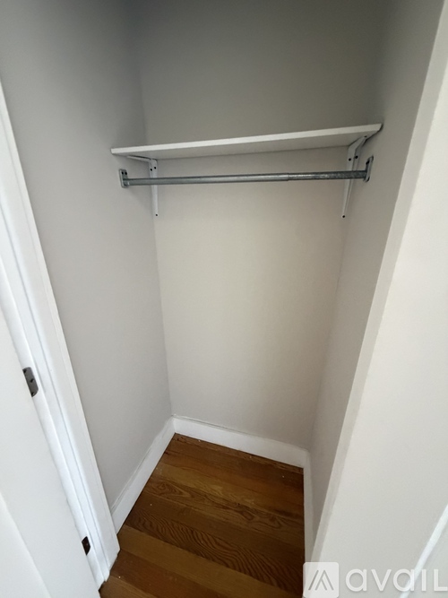 A white closet with a shelf and a door.