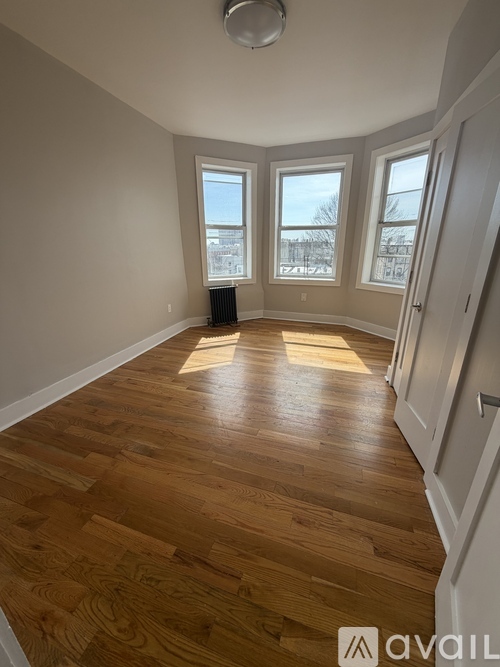 A room with wooden flooring and a window overlooking a snowy landscape.