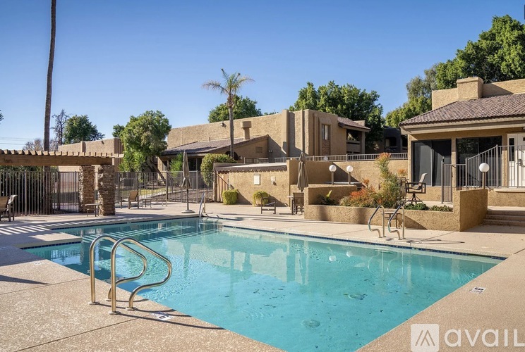A pool surrounded by a fence and a building in the background.