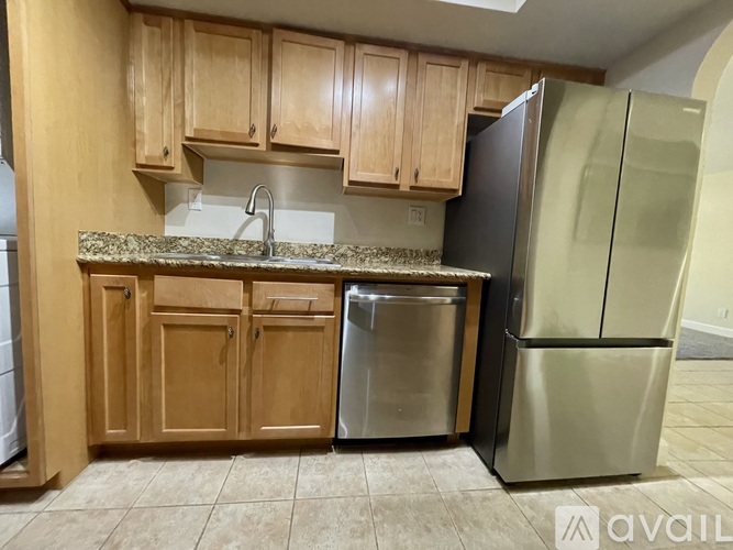 A kitchen with wooden cabinets and a black fridge.
