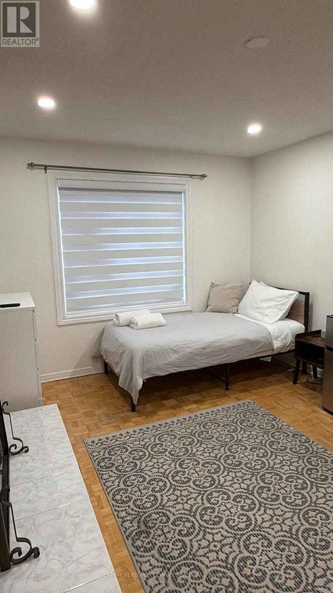 A bedroom with a bed, a window with blinds, and a rug on the floor.