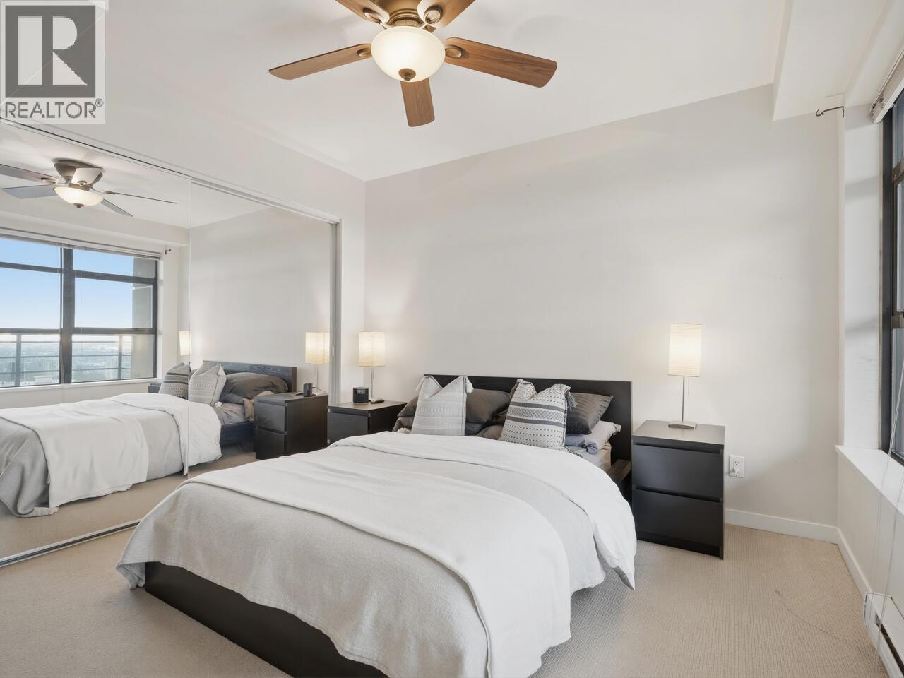 A bedroom with a large bed and a ceiling fan.