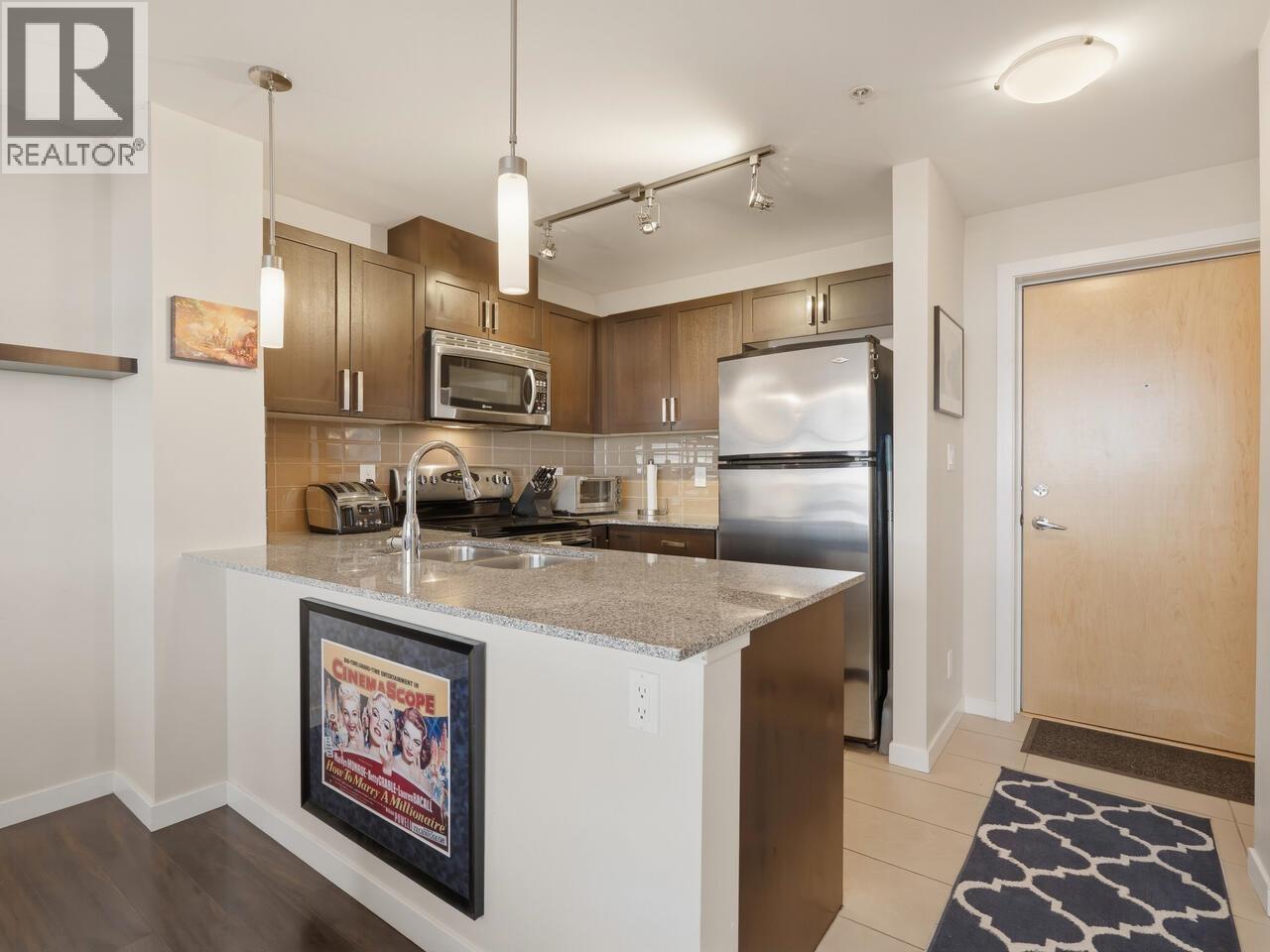A kitchen with a fridge, microwave, and oven.