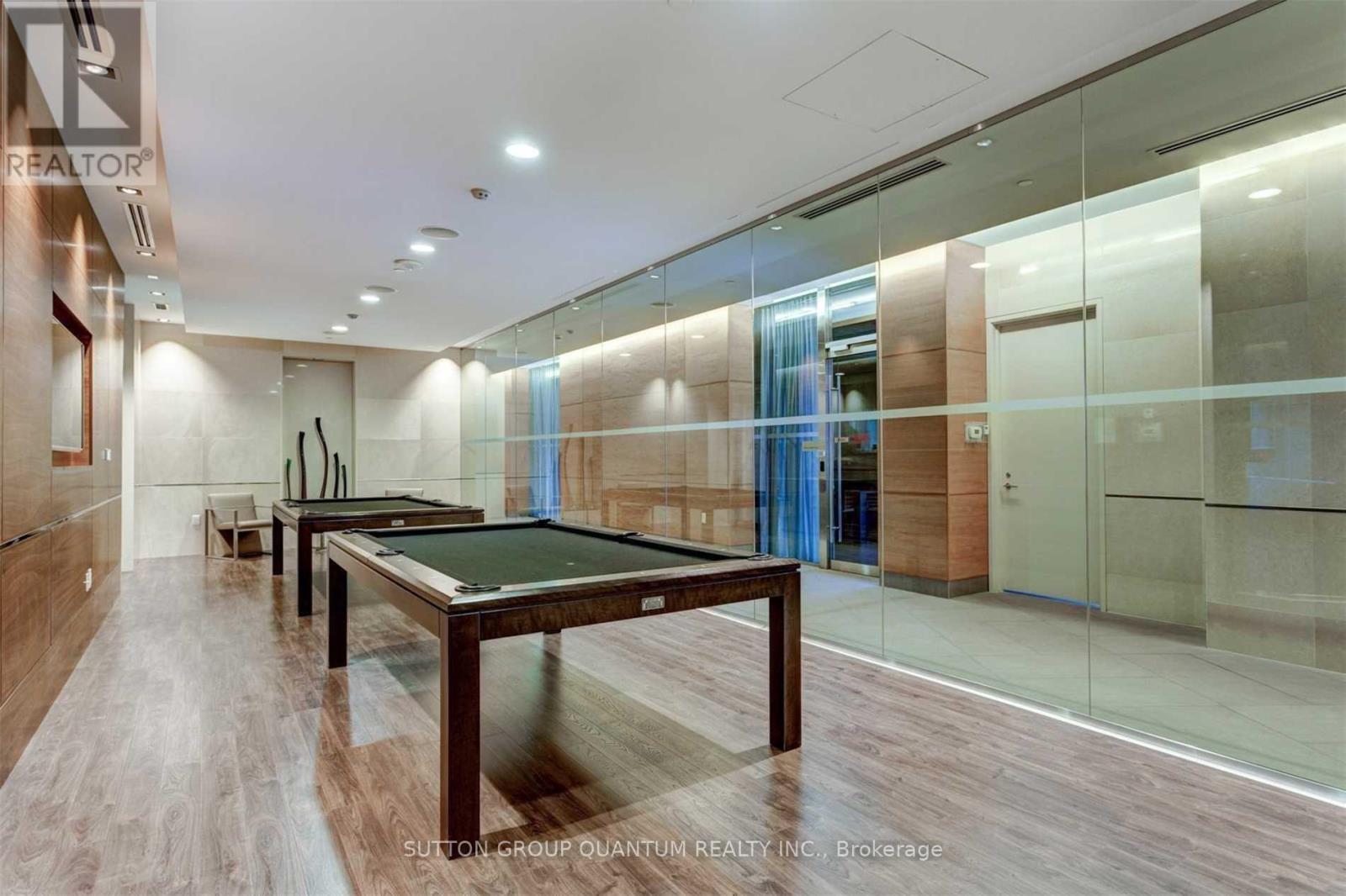 A pool table in a room with wood flooring and glass walls.
