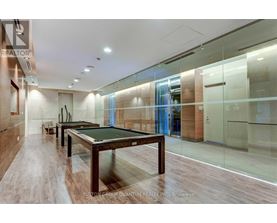 A pool table in a room with wood flooring and glass walls.