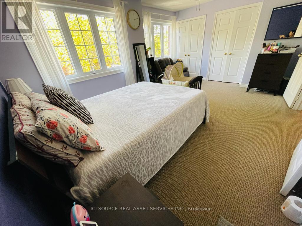 A bedroom with a large bed and a window with white curtains.