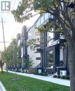 A modern building with glass windows and a tree in front.