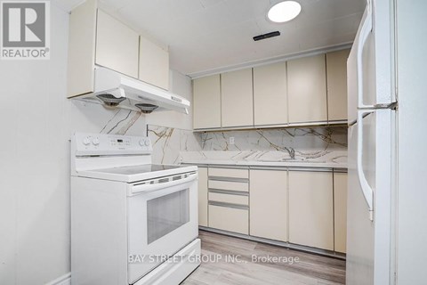 A white oven and refrigerator in a kitchen with beige cabinets.
