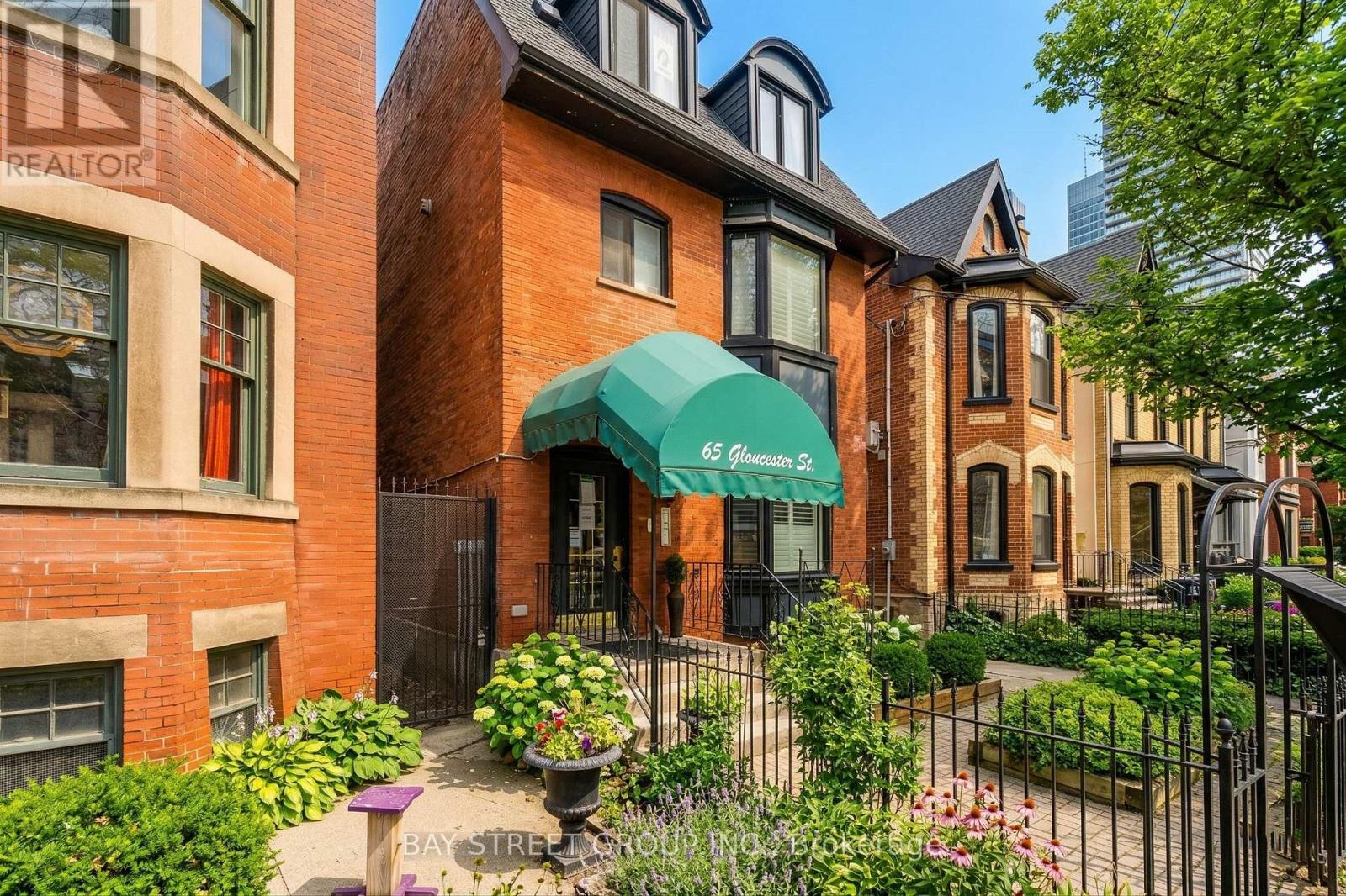 A red brick house with a green awning on the front.