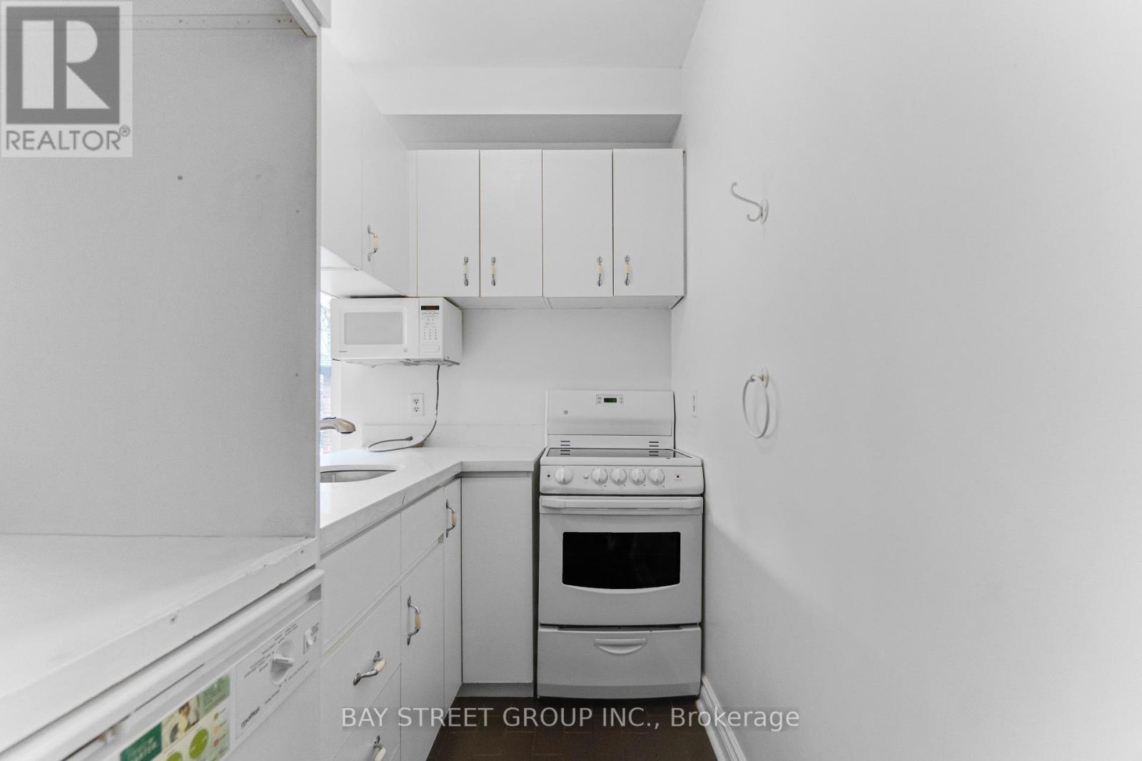 A white kitchen with a stove top oven and a microwave.