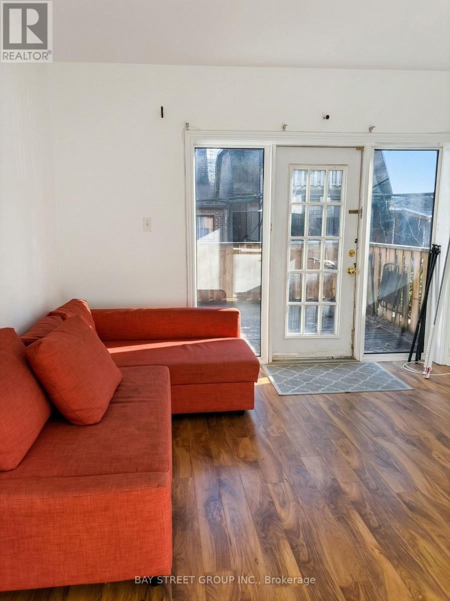 A living room with a red couch and a wooden floor.