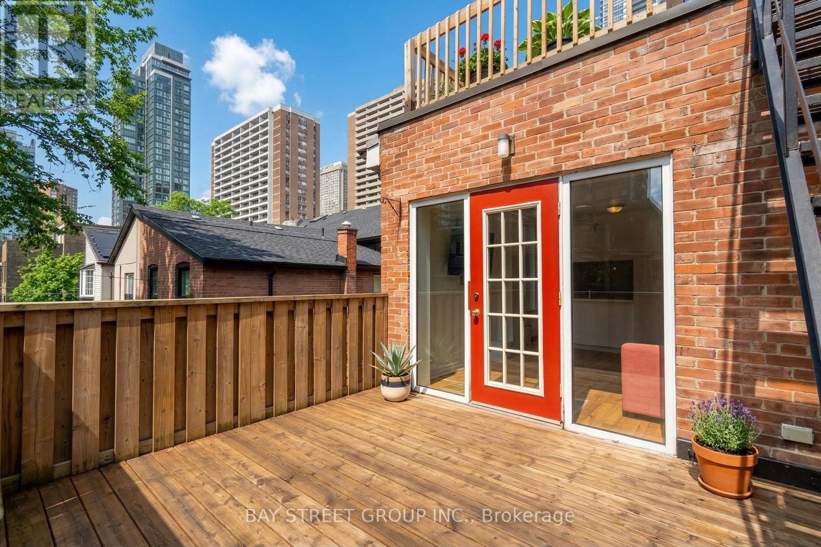 A red door is on the side of a brick building.