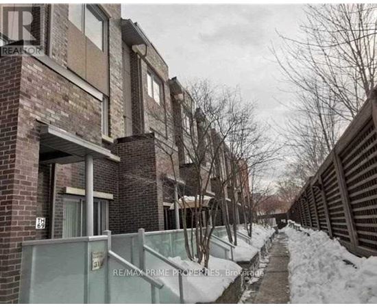 A snowy pathway leads to a brick building with a sign that reads "RE/MAX Prime Properties, Brokerage.".
