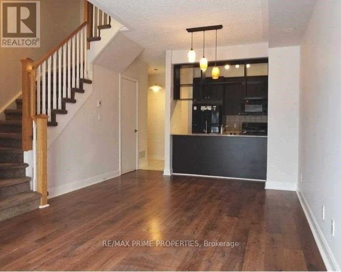 A spacious living room with wooden floors and a staircase.