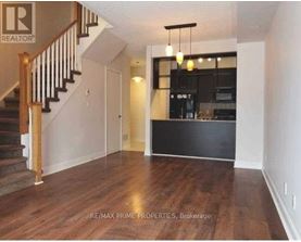 A spacious living room with wooden floors and a staircase.
