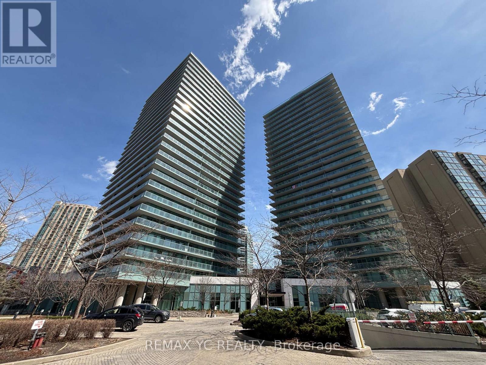 Two tall buildings with glass windows and a clear blue sky in the background.
