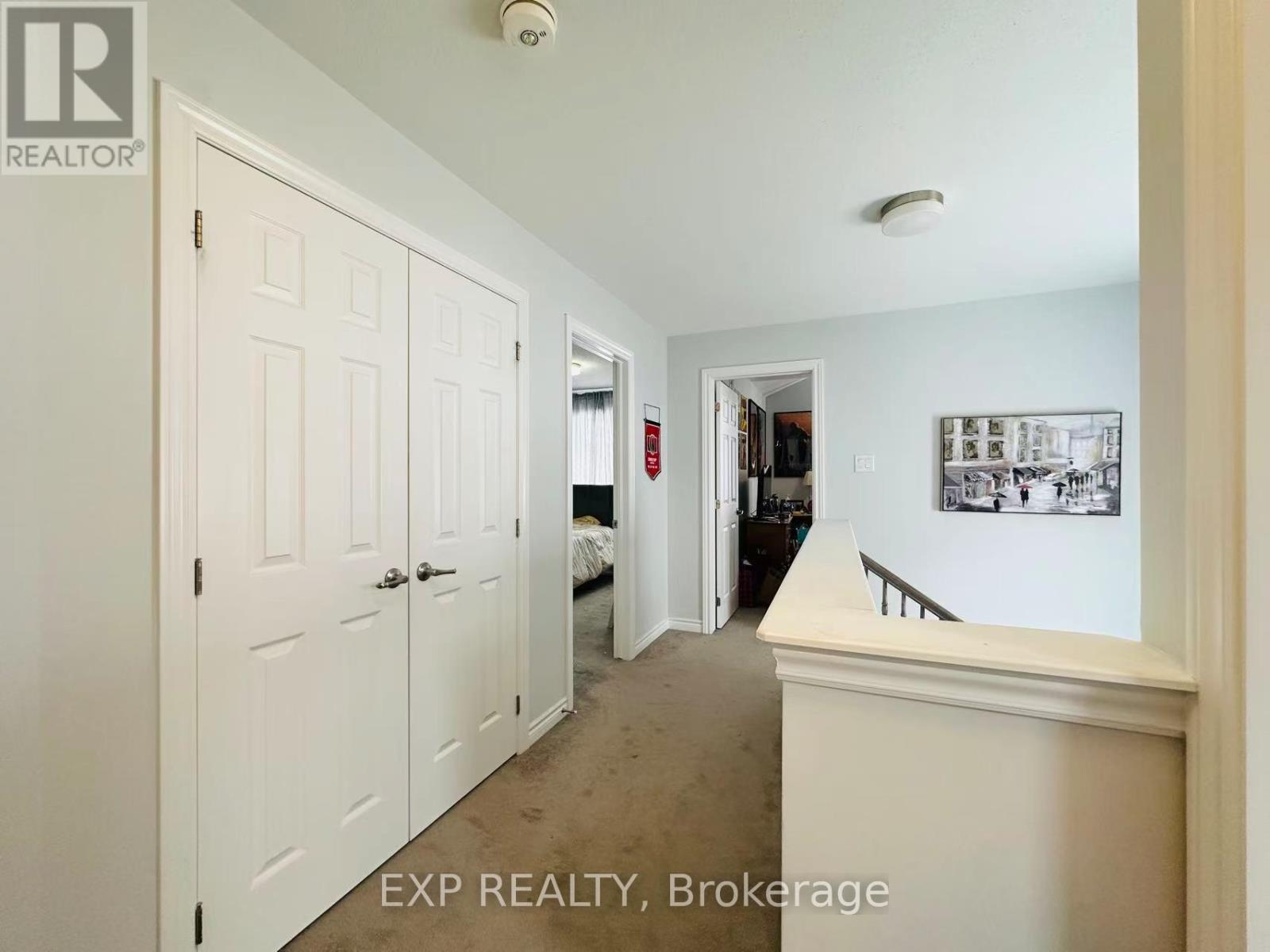 A hallway with a door on the left and a bedroom on the right.