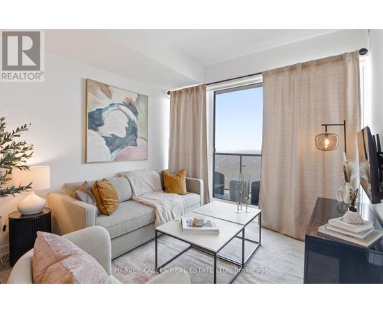 A living room with a grey couch, a coffee table, and a painting on the wall.