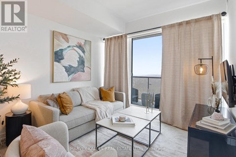 A living room with a grey couch, a coffee table, and a painting on the wall.