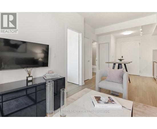A living room with a flat screen TV, a black cabinet, a white chair, and a magazine on the coffee table.