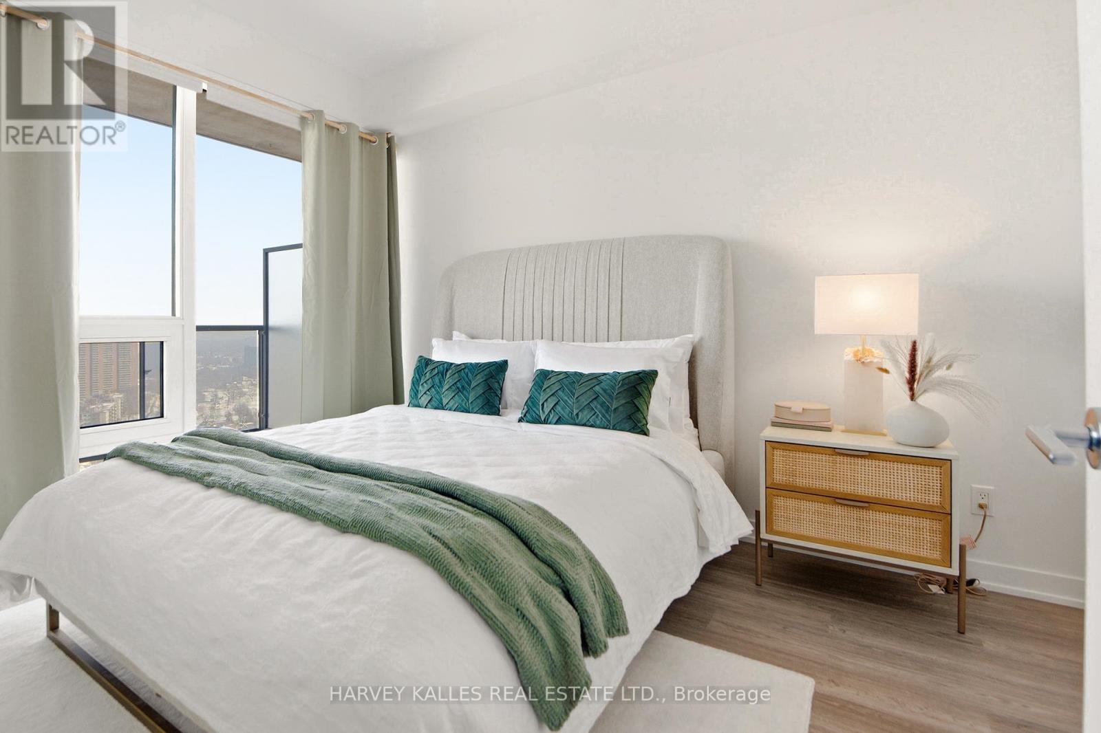 A bedroom with a large bed and a nightstand with a lamp.