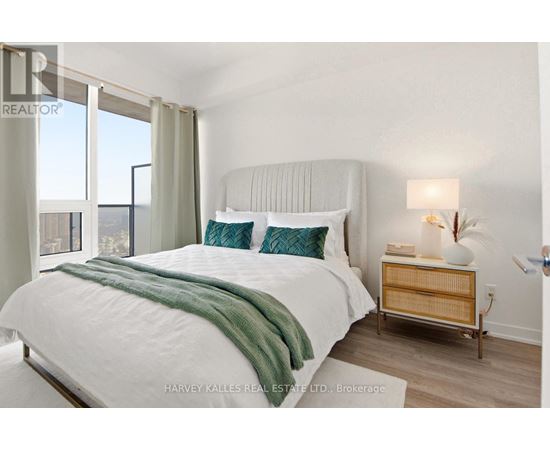A bedroom with a large bed and a nightstand with a lamp.