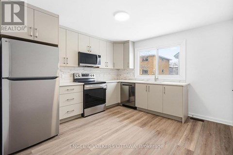 A kitchen with a refrigerator, microwave, oven, and sink.