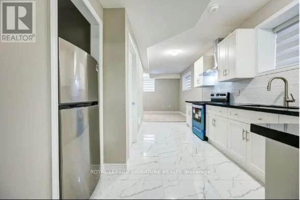 A kitchen with white cabinets and a marble floor.