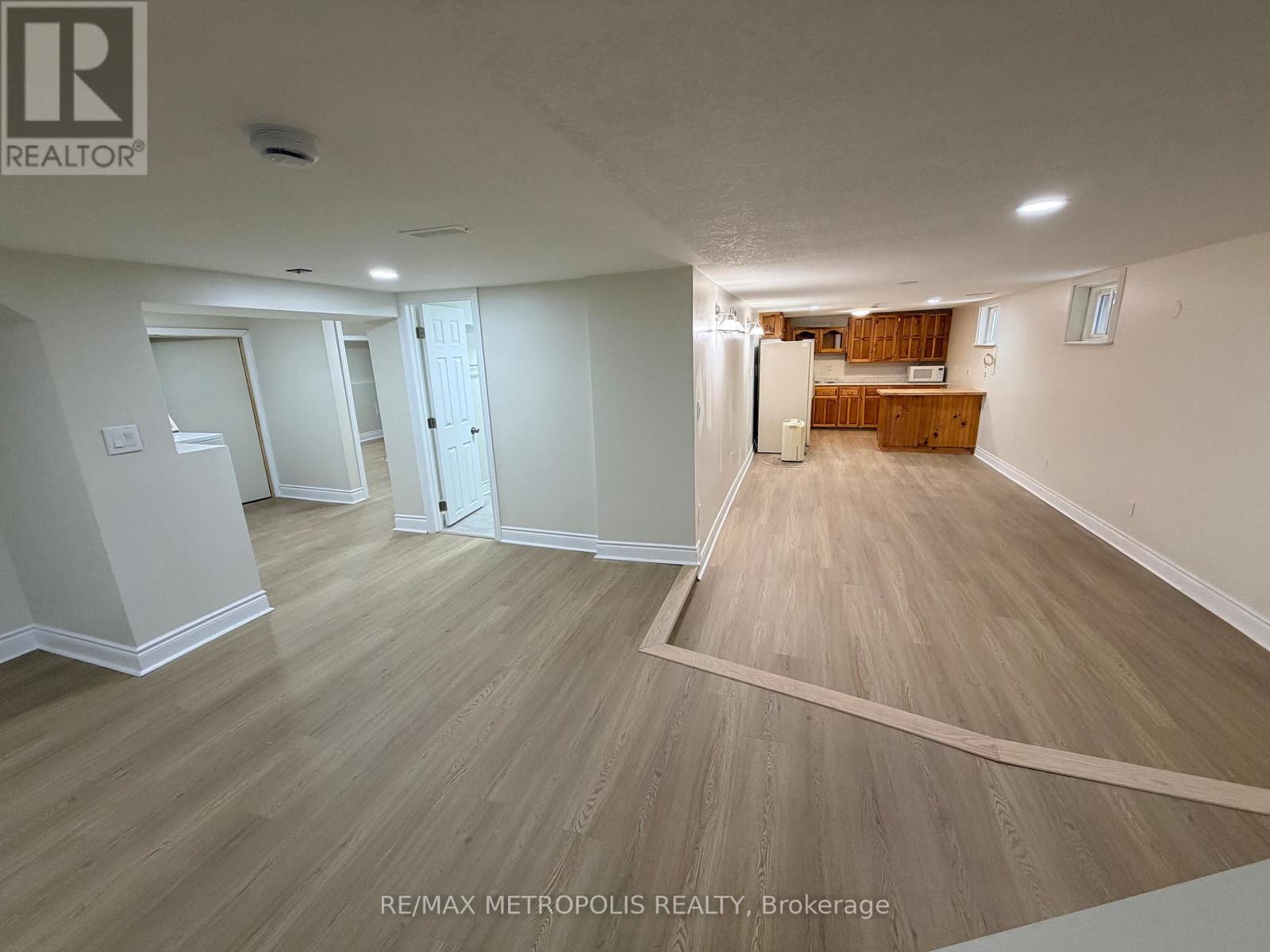 A spacious room with wooden flooring and white walls.