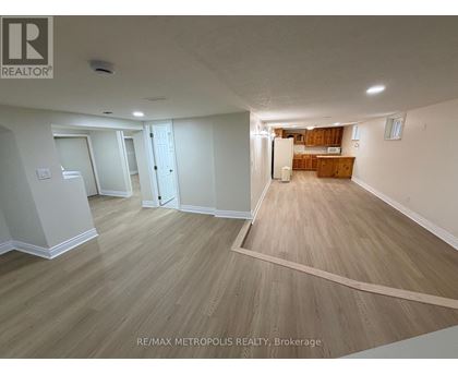 A spacious room with wooden flooring and white walls.