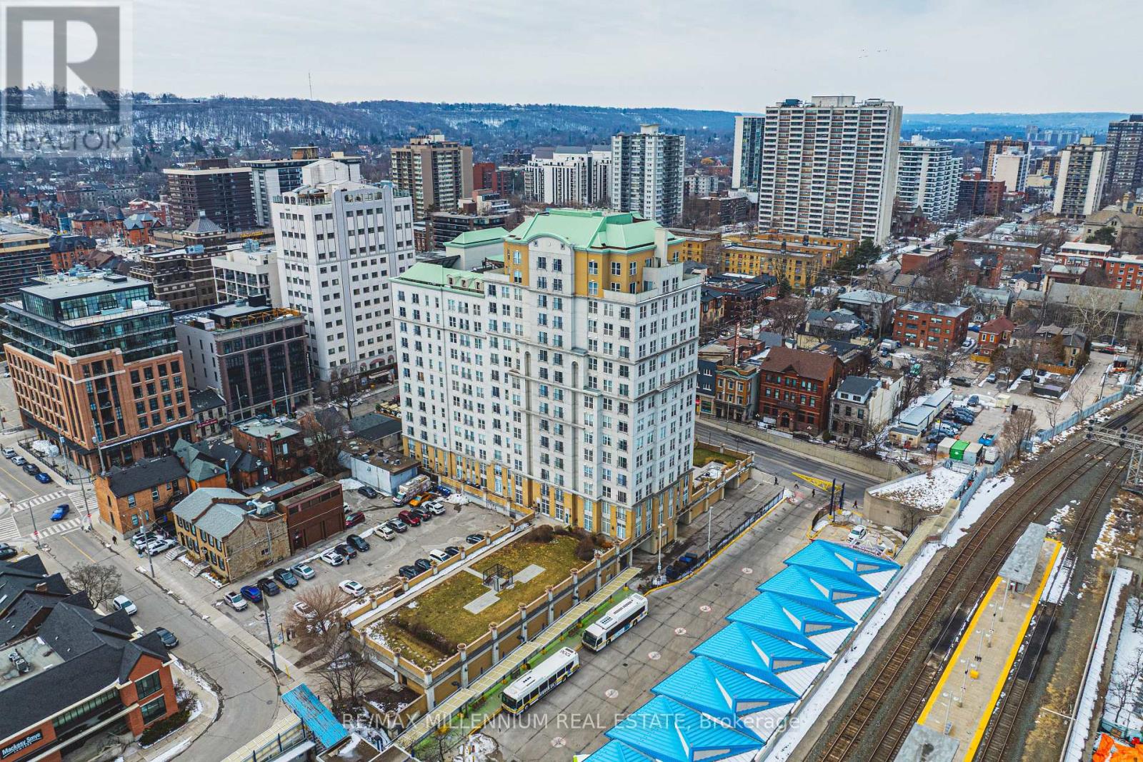 A cityscape with a large white building in the center and a train track running through the scene.