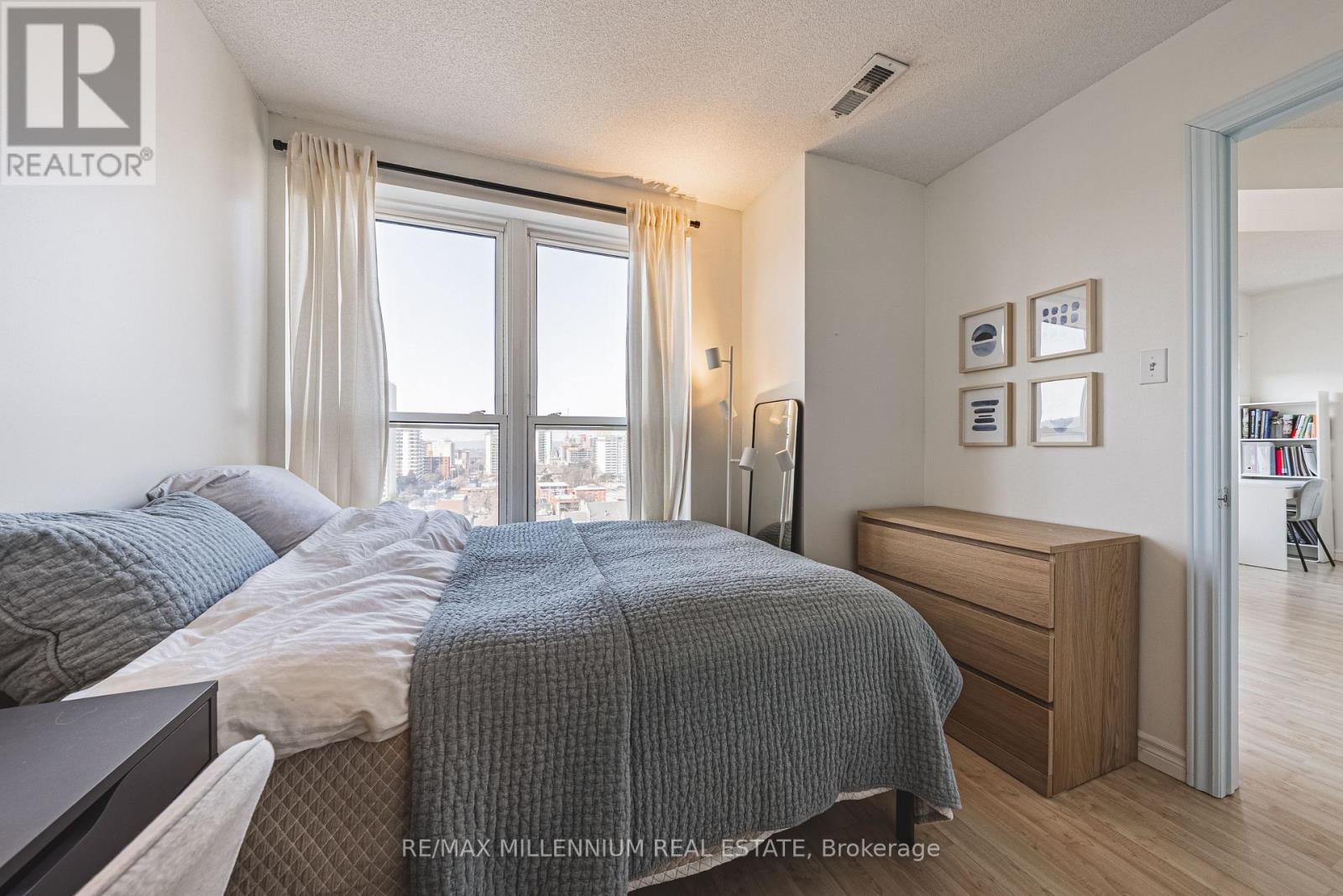 A bedroom with a large bed and a window overlooking the city.