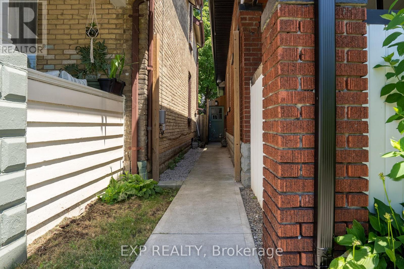 A narrow alleyway between two buildings with a sign that reads "EXP REALTY, Brokerage".