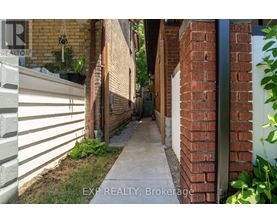 A narrow alleyway between two buildings with a sign that reads "EXP REALTY, Brokerage".