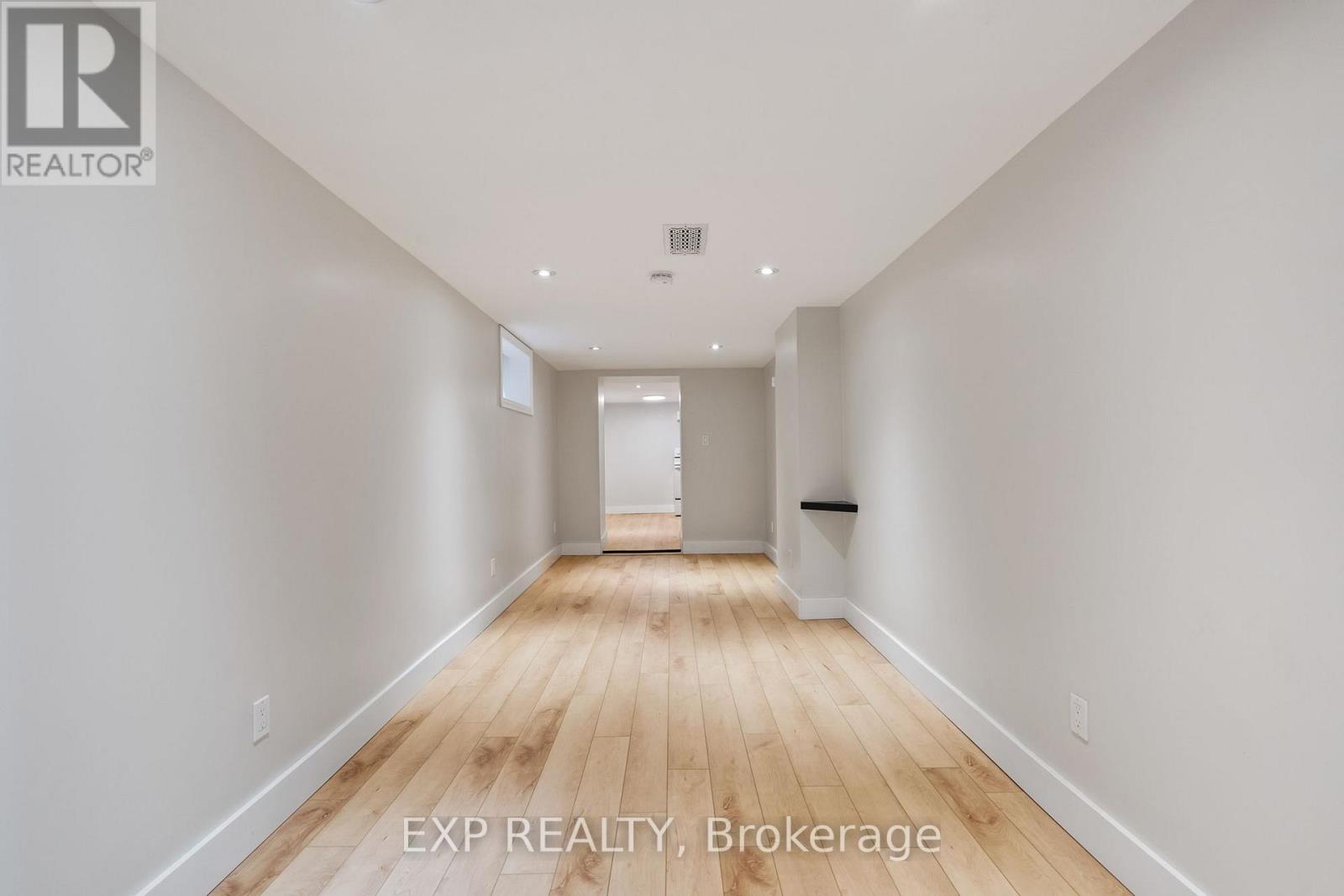 A long, empty hallway with wooden floors and white walls.