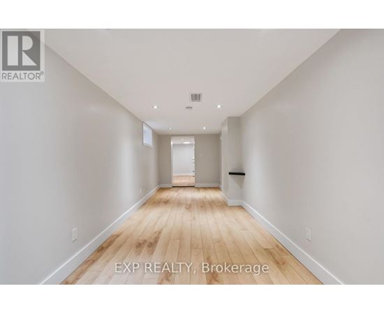 A long, empty hallway with wooden floors and white walls.