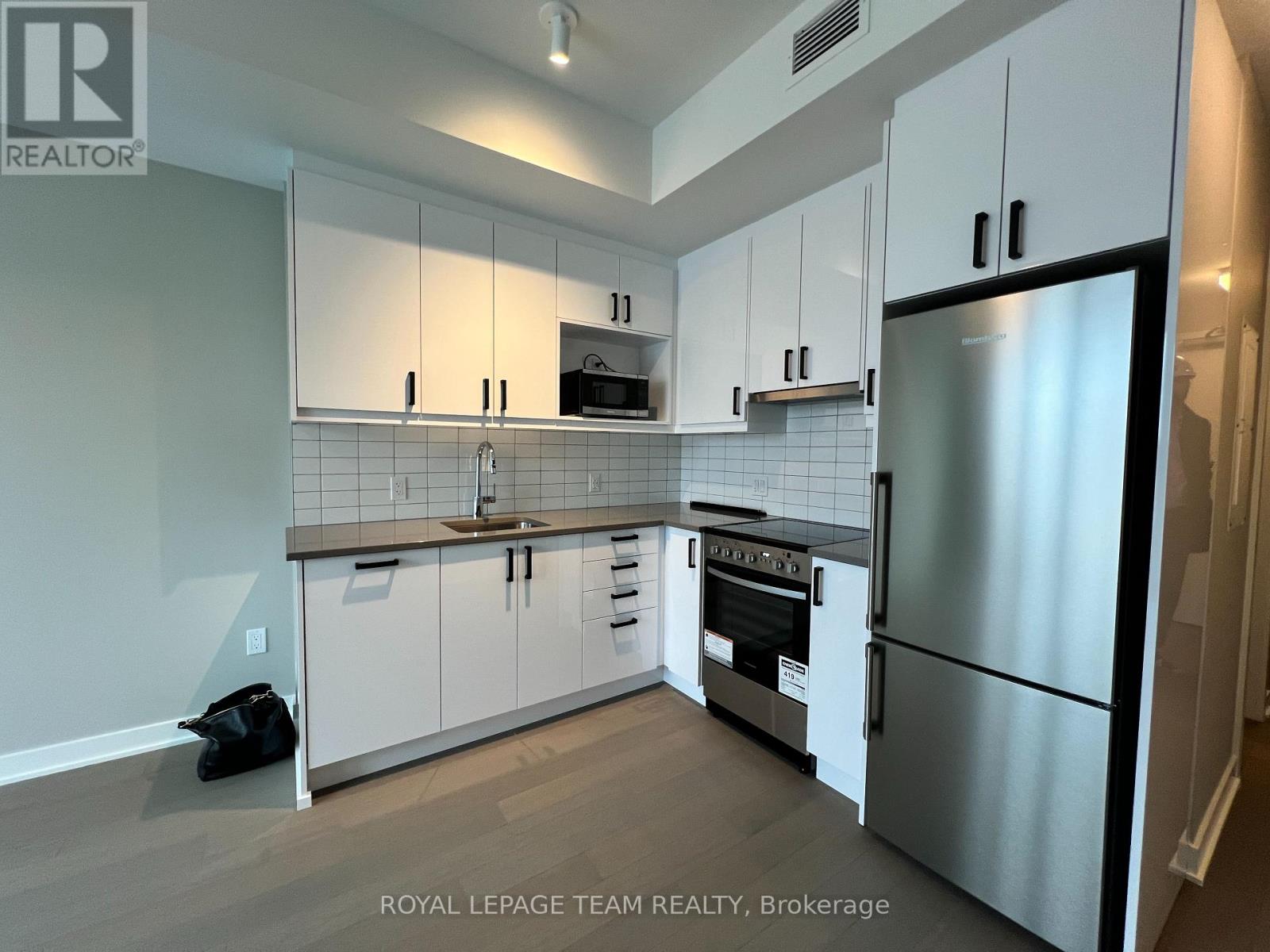 A kitchen with white cabinets and a stainless steel refrigerator.
