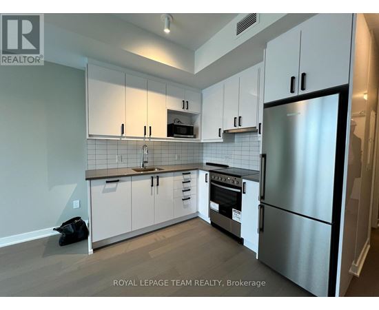A kitchen with white cabinets and a stainless steel refrigerator.