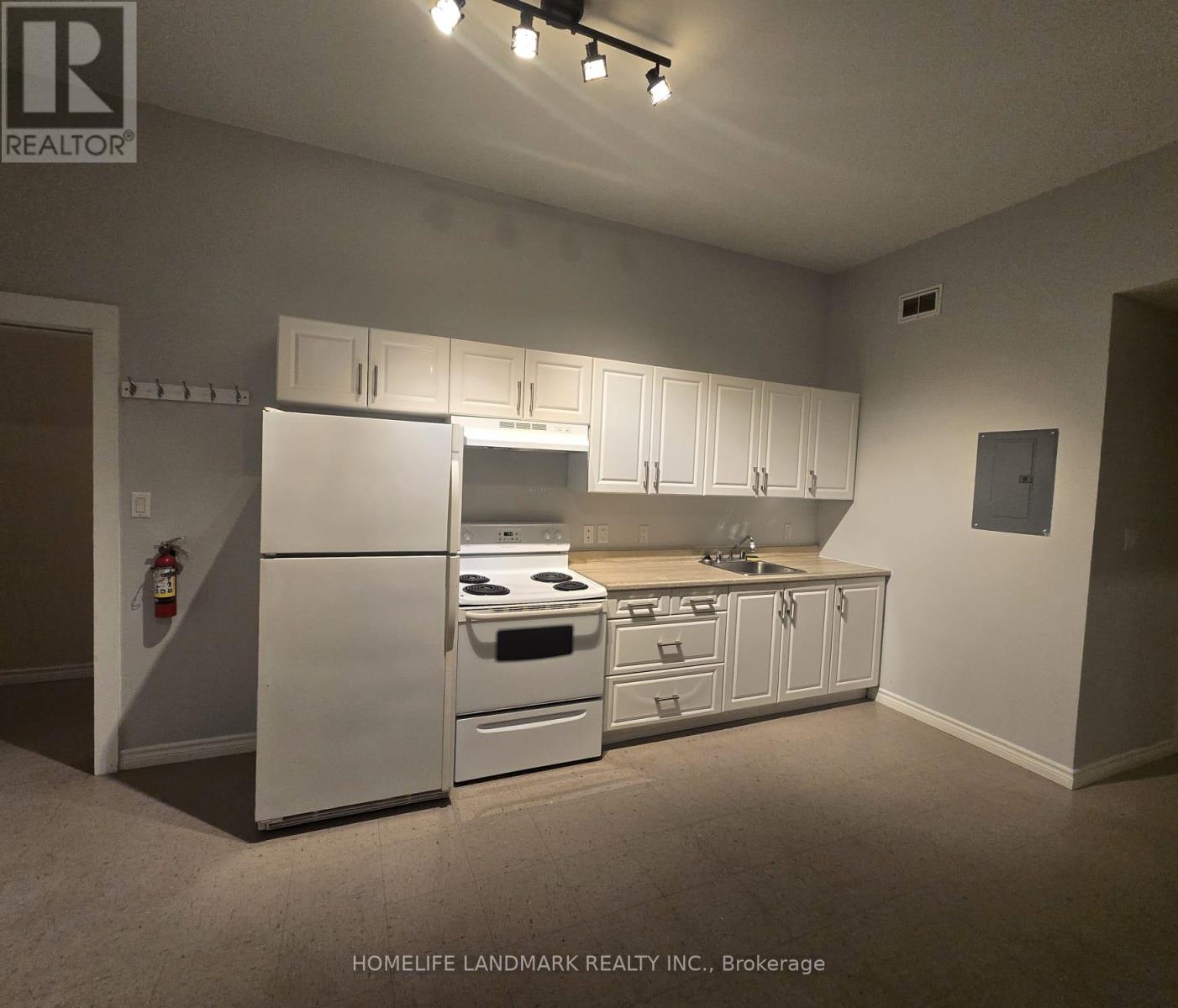 A kitchen with white appliances and cabinets in a real estate office.