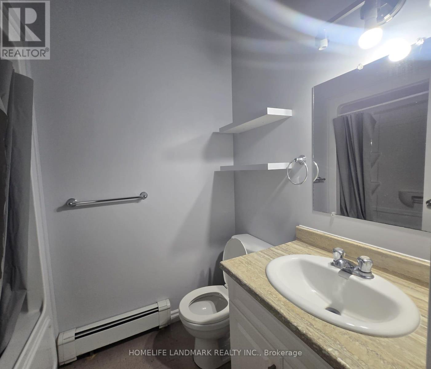 A bathroom with a sink, toilet, and mirror.