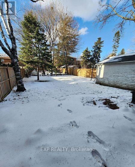 A snow-covered backyard with trees and a fence.