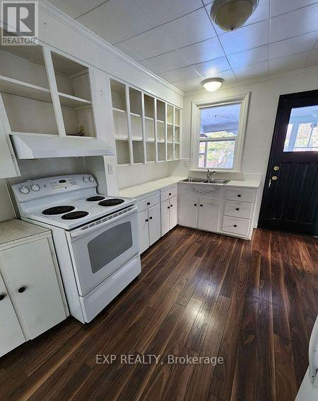 A kitchen with white appliances and wooden floors.